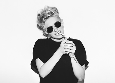 Blonde woman wearing sunglasses lighting a cigarette